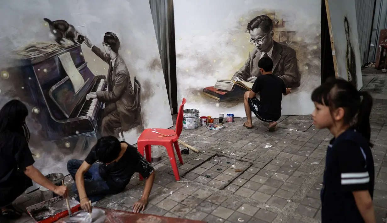 Mahasiswa menyelesaikan lukisan mendiang raja Bhumibol Adulyadej dengan sosok seorang yang sedang bermain piano dan membaca buku di Universitas Silpakorn, Bangkok, Senin (17/10). (Reuters/Athit Perawongmetha)