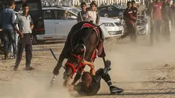 Seorang joki terjatuh saat mengikuti balap kuda di Rafah, Jalur Gaza, Palestina, Selasa (10/9/2019). Balapan kuda tradisional Palestina tersebut digelar di bekas lokasi bandara Jalur Gaza yang telah hancur. (AFP Photo/Said Khatib)