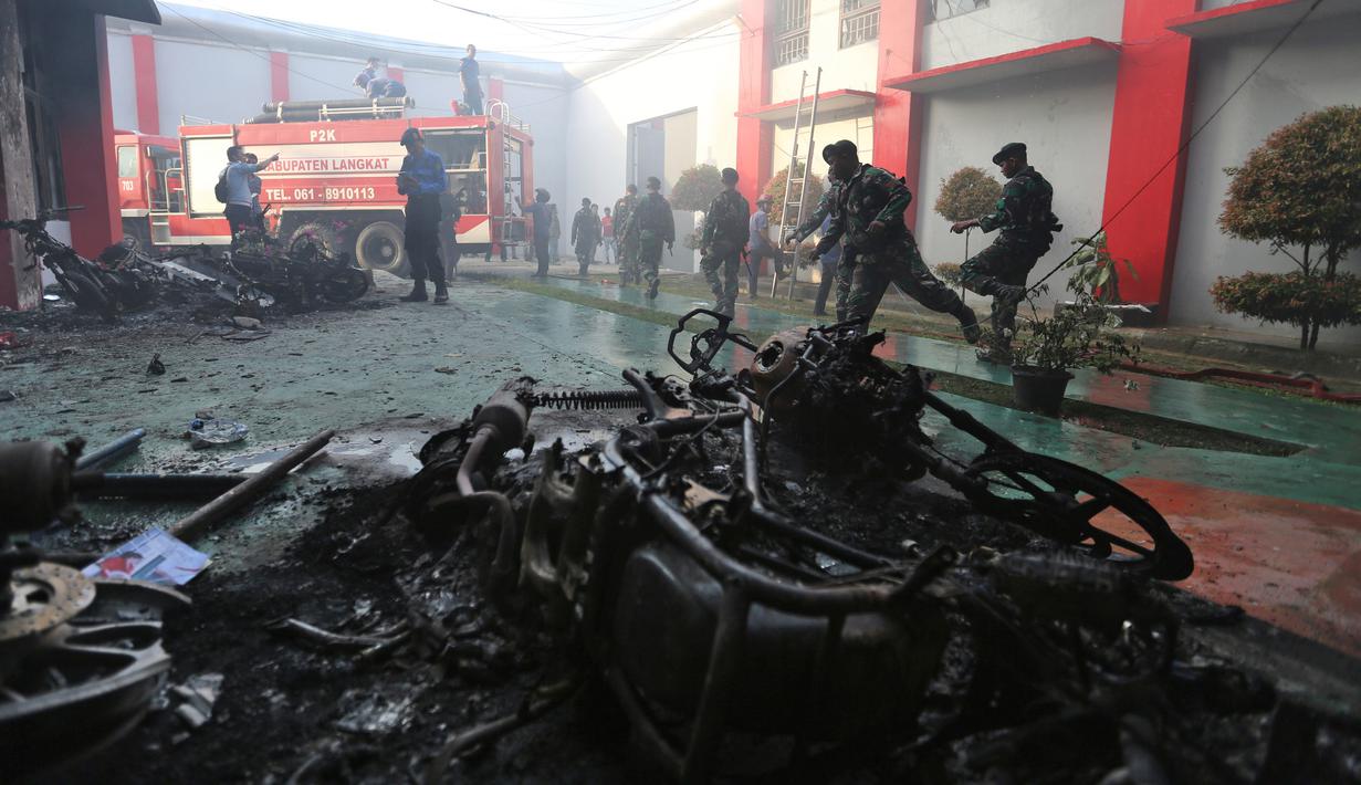 Petugas Lapas Narkotika Kelas III Langkat memeriksa kerusakan setelah kerusuhan di Langkat, Sumatera Utara, Kamis (16/5/2019). Akibat peristiwa kerusuhan yang dilakukan para narapidana di Lapas tersebut mengakibatkan tiga mobil petugas rusak terbakar dan ratusan napi melarikan diri. (AP Photo)