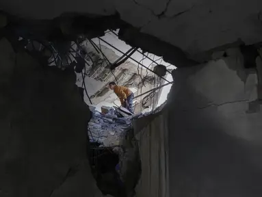 Seorang pemuda Palestina memeriksa kerusakan di dalam sebuah bangunan yang terkena serangan pada 15 April 2025 malam oleh Israel di distrik barat daya Jabalia, Nazla, di Jalur Gaza utara, 16 April 2025. (BASHAR TALEB/AFP)