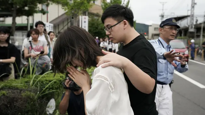 Seorang wanita berdoa untuk para korban kebakaran  di gedung Kyoto Animation Studio di Kyoto, Jepang (19/7/2019). Pihak kepolisian masih menyelidiki penyebab kebakaran, namun polisi menduga kebakaran tersebut atas unsur kesengajaan. (AP Photo/Jae C. Hong)