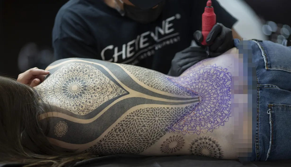 Seorang wanita terbaring saat ditato dalam acara Sao Paulo Tattoo Week, Brasil, Jumat (25/10/2019). (AP Photo/Andre Penner)