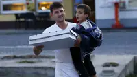 Seorang pelayan tampan terlihat membagikan pizza ke anak-anak di perbatasan Slovenia.