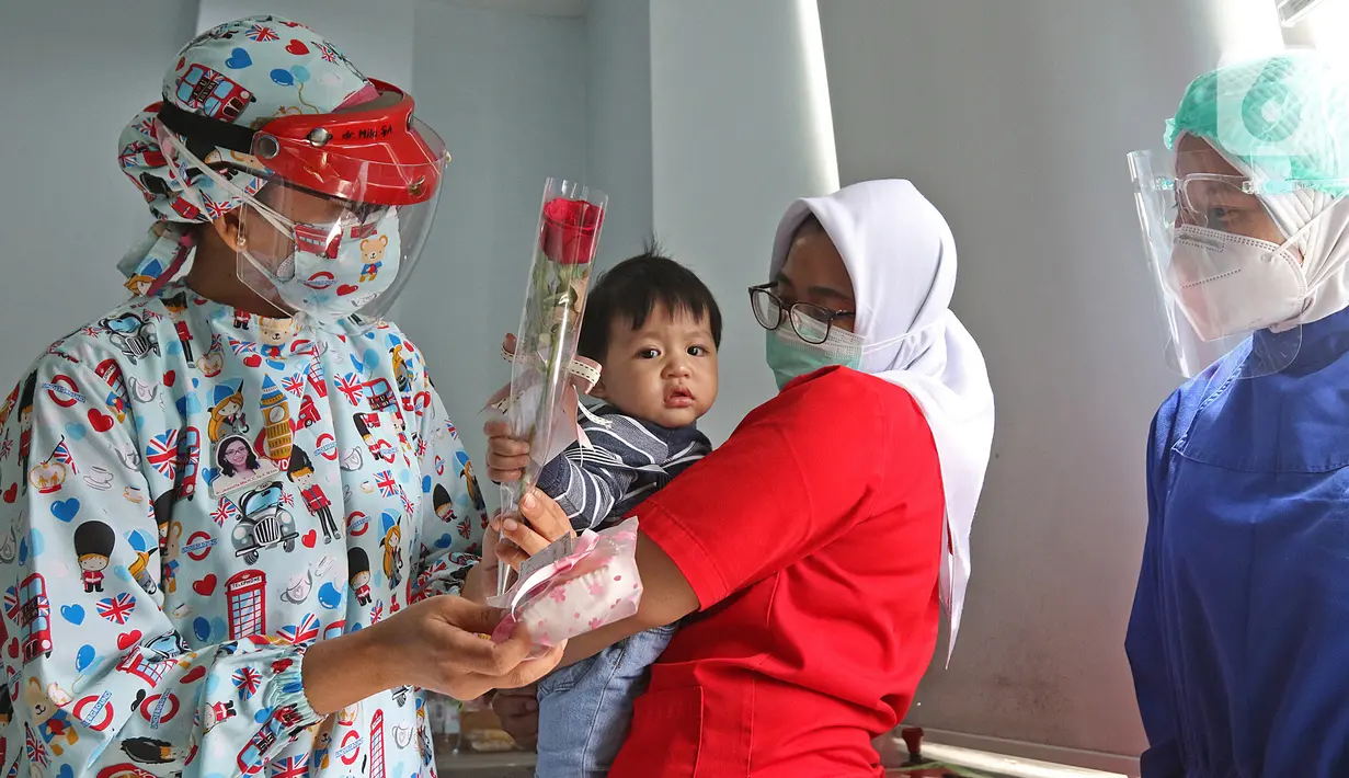 Dokter anak J. Mila Hardiani memberikan bunga dan kue ke pasien di Rumah Sakit Ibu dan Anak Tambak, Jakarta, Selasa (22/12/2020). Pemberian bunga dan kue kepada pasien rawat inap dan pasien yang kontrol dilakukan untuk memperingati perayaan Hari Ibu. (Liputan6.com/Herman Zakharia)