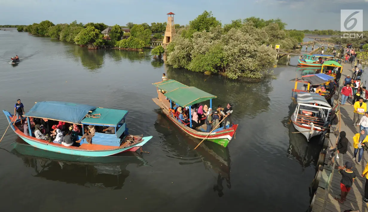 Perahu wisata melintasi kerumunan wisatawan yang berjalan di atas Jembatan Cinta di Wisata Mangrove, Tarumajaya, Bekasi, Minggu (30/12). Wisata tersebut berbatasan langsung dengan kawasan Marunda Jakarta Utara. (merdeka.com/Arie Basuki)