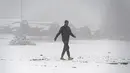 Seorang imigran berjalan saat hujan salju di Kamp Lipa, luar Bihac, Bosnia, Jumat (8/1/2021). Cuaca bersalju dan musim dingin telah membawa lebih banyak penderitaan bagi ratusan imigran yang terjebak selama berhari-hari di kamp tersebut. (AP Photo/Kemal Softic)