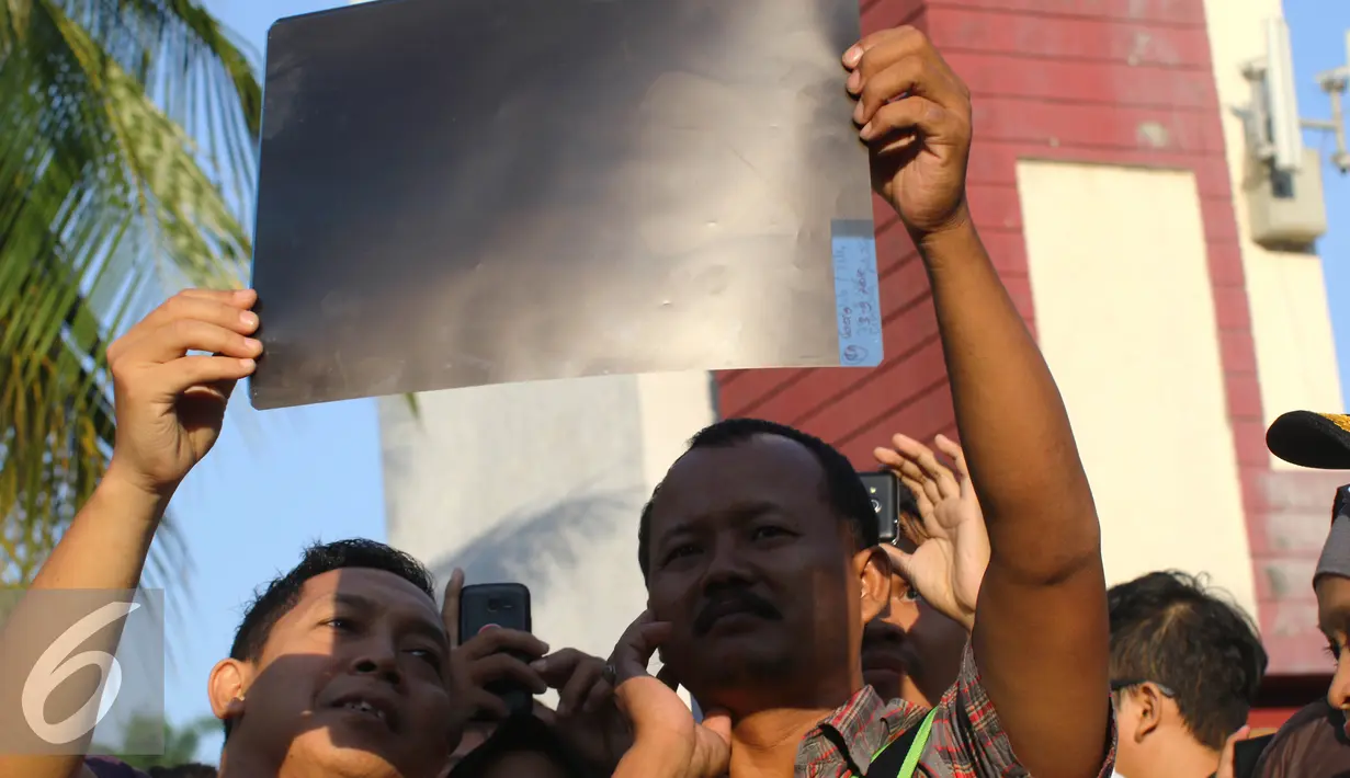 Warga mengunakan film bekas ronsen melihat proses Gerhana Matahari Total (GMT) 2016 di halaman Taman Ismail Marzuki (TIM), Jakarta, Rabu (9/3). Fenomena alam ini terjadi setiap 350 tahun. (Liputan6.com/Fery Pradolo)