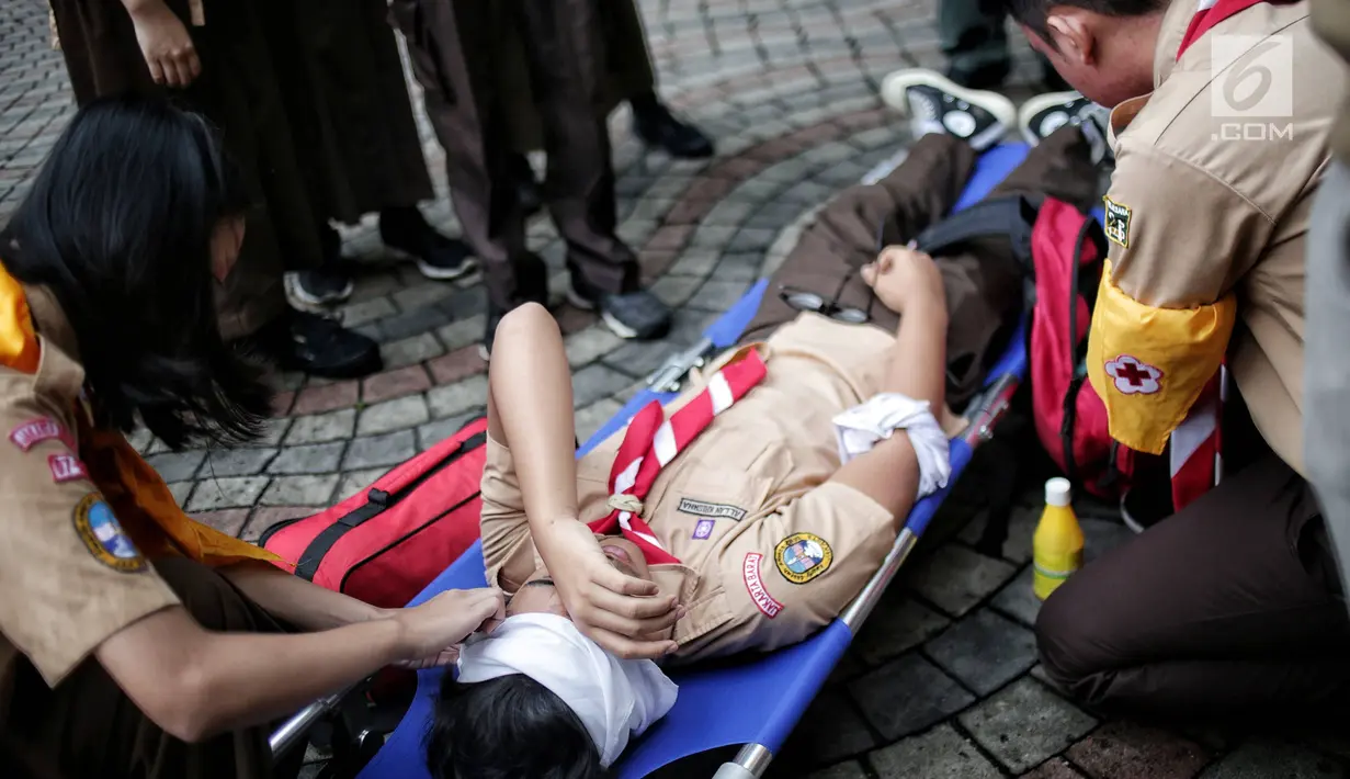 Sejumlah siswa memberikan pertolongan pertama saat simulasi bencana di SMAN 78 Jakarta, Rabu (23/1). Kegiatan itu untuk pengenalan kepada siswa-siswi dengan program siaga bencana berupa simulasi evakuasi gempa dan tsunami. (Liputan6.com/Faizal Fanani)