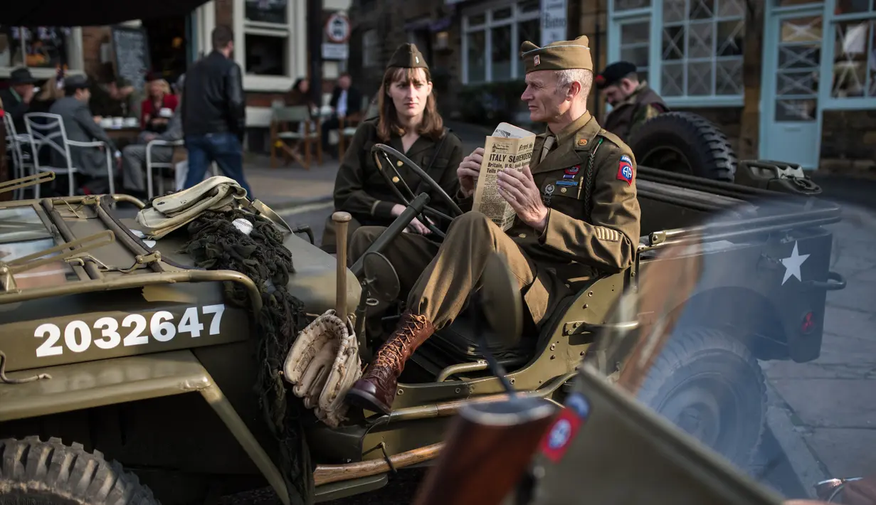 Reenactor Perang Dunia II mengenakan pakaian tentara duduk diatas Jip saat mengikuti 'Railway in Wartime Event' yang ke 25 di Pickering, Inggris (15/10). Reenactor adalah para penggiat sejarah yang mirip dengan cosplayer. (AFP Photo/Oli Scarff)