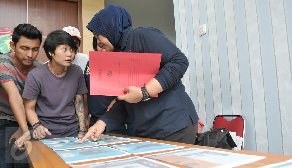 Petugas DVI Polri menunjukan ke pihak keluarga foto properti hasil postmortem sekunder dari jenazah Korban KM Zahro di RS Polri, Jakarta, Selasa (3/1). (Liputan6.com/Yoppy Renato)