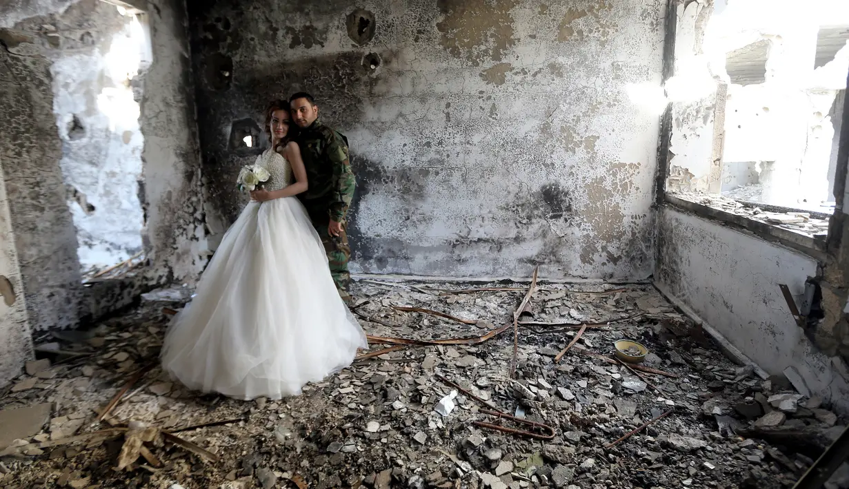 Pengantin baru, Nada Merhi (18) dan Hassan Youssef (27) berfoto di puing bangunan kota Homs yang jadi medan perang, Suriah, 5 Februari 2016. Foto ini seolah bukti meski di tengah kehancuran, hidup terus berlalu dan harapan akan terus ada. (JOSEPH EID/AFP)