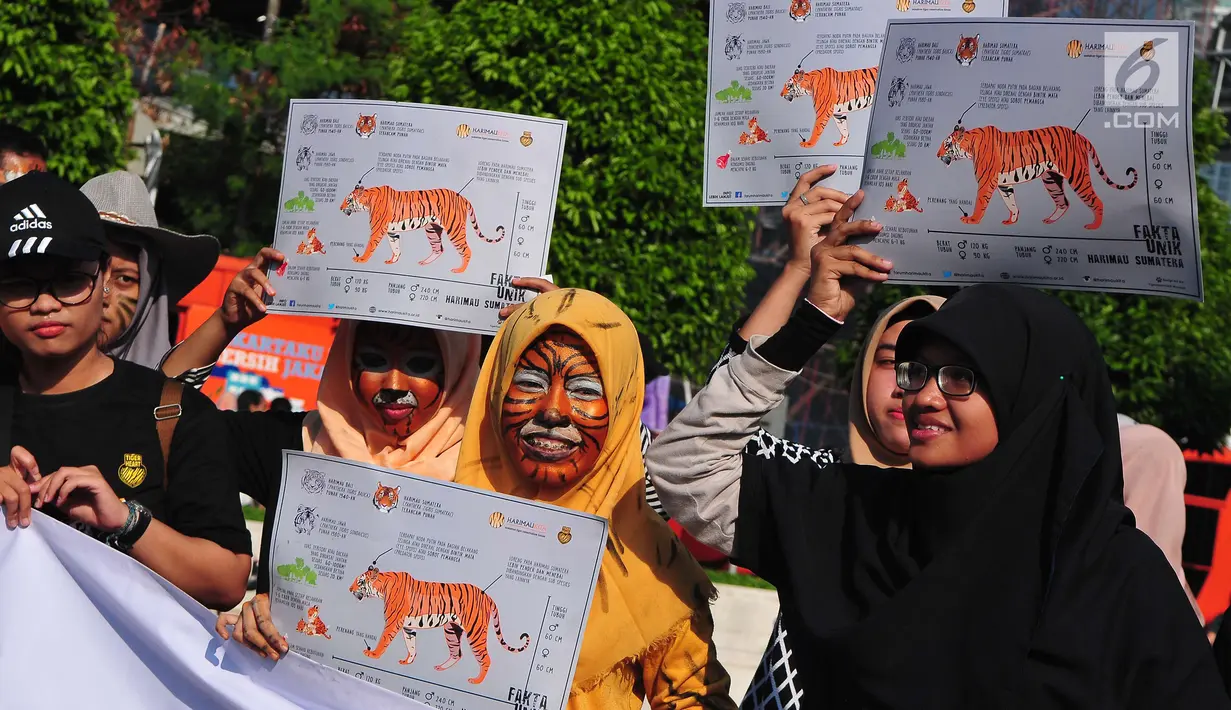 Peserta aksi dari forum harimaukita membentangkan spanduk dan poster saat mengkampanyekan Global Tiger Day di Bundaran HI, Jakarta, Minggu (30/7). (Liputan6.com/Helmi Afandi)