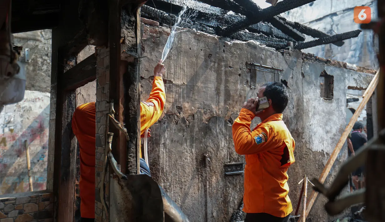 Petugas pemadam kebakaran melakukan proses pendinginan dengan menyemprotkan air ke puing bangunan untuk memastikan tidak ada titik api yang kembali menyala pascakebakaran di Jalan Kramat Pulo Dalam, Senen, Jakarta Pusat, Jumat (9/10/2026). (KLY/Budy Santoso)