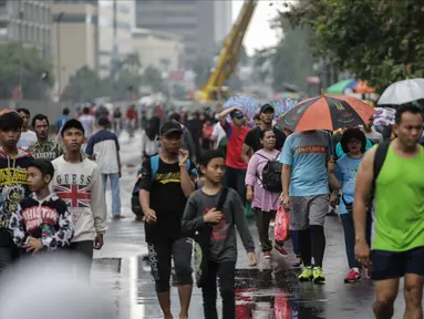 Warga melakukan olahraga dalam kegiatan rutin hari bebas kendaraan bermotor atau car free day di kawasan Bunderan HI, Jakarta, Minggu (4/2). Walaupun gerimis mengguyur tidak menyurutkan minat masyarakat yang melakukan olahraga.(Liputan6.com/Faizal Fanani)