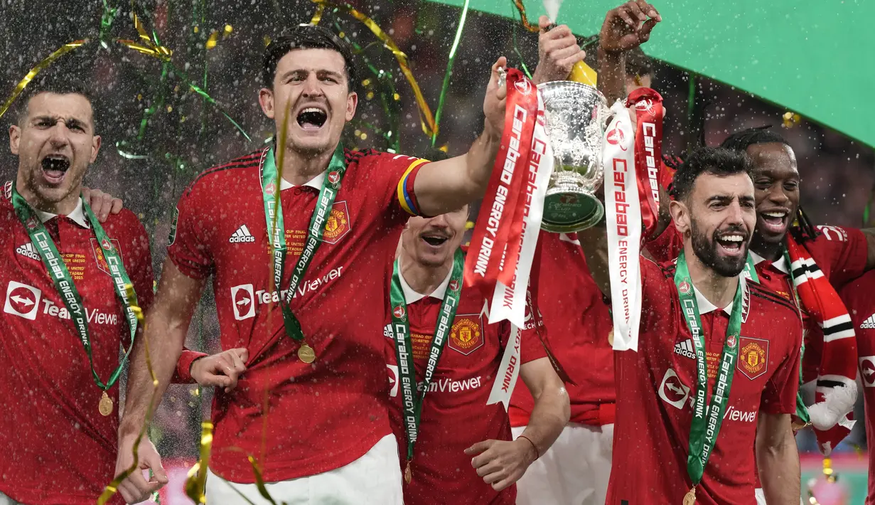 <p>Pemain Manchester United atau MU Bruno Fernandes (kanan tengah) dan Harry Maguire merayakan trofi juara Carabao Cup 2022/2023 usai kalahkan Newcastle United pada partai final di Stadion Wembley, Senin dini hari WIB (27/2/2023). Keberhasilan ini menuntaskan puasa trofi terpanjang Setan Merah. (AP Photo/Alastair Grant)</p>