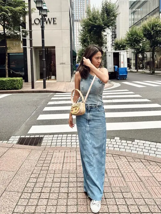 Gaya denim on denim ala Azizah Salsha. Ia mengenakan denim top dengan bahu asimetris dan rok denim panjang. Ia padukan dengan mini sling bag berwarna cokelat. [Foto: Instagram/azizahsalsha_]