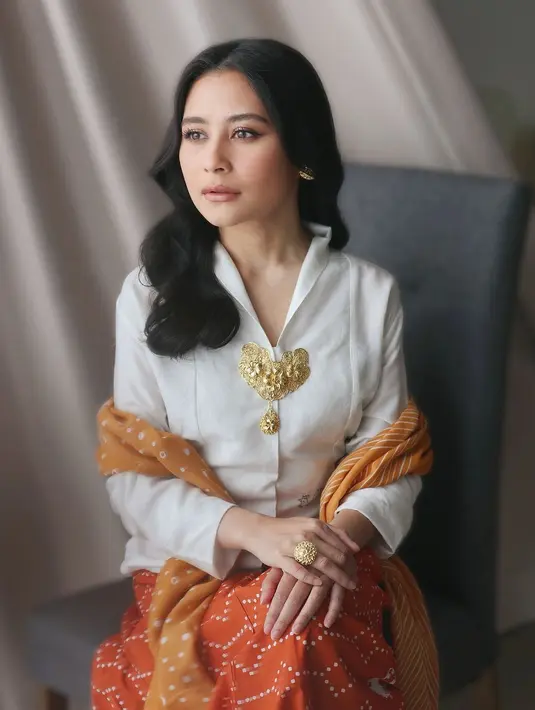 Prilly Latuconsina menunjukkan pesona anggun sebagai seorang Kartini Masa Kini dengan mengenakan kebaya kartini warna putih yang dipadukan kain batik dan selendang nuansa kuning-oranye. [@prillylatuconsina96].