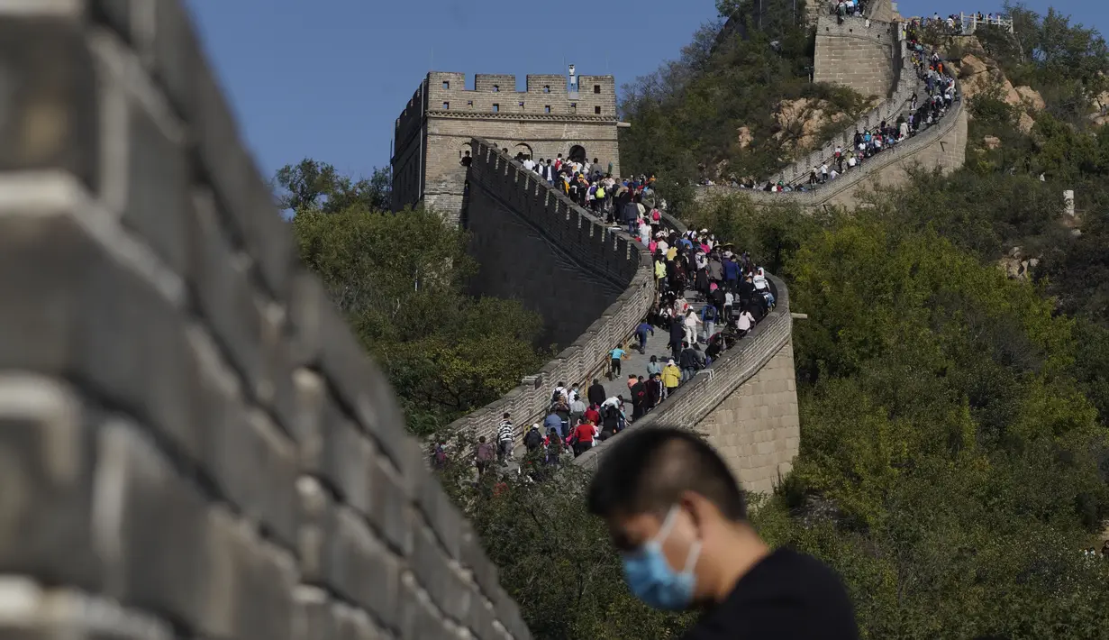 Seorang pria yang mengenakan masker untuk membantu melindungi dari virus corona berdiri di dekat hamparan Tembok Besar China di pinggiran Beijing (6/10/2020). (AP Photo/Ng Han Guan)