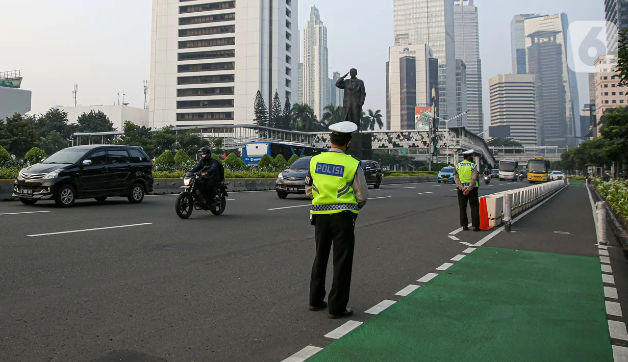 Polisi saat menertibkan pesepeda yang berada di luar jalur di kawasan Sudirman-Thamrin, Jakarta Pusat, Rabu (2/6/2021). Sepeda road bike diperbolehkan untuk melintas di Jalan Sudirman-Thamrin pada hari kerja Senin-Jumat, namun dibatasi dari pukul 05.00-06.30 WIB. (Liputan6.com/Faizal Fanani)