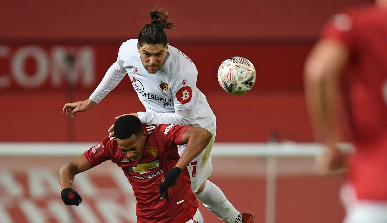 Bek Watford, Francisco Sierralta (atas) berduel udara dengan striker Manchester United, Anthony Martial dalam laga babak ke-3 Piala FA 2020/21 di Old Trafford, Sabtu (9/1/2021). Watford kalah 0-1 dari Manchester United. (AFP/Oli Scarff/Pool)