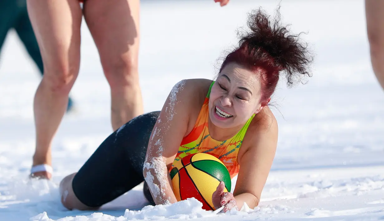 Seorang wanita mengenakan pakaian renang menangkap bola saat bermain di lapangan bersalju di Shenyang, Provinsi Liaoning, Tiongkok (8/3). (AFP Photo/China Out)