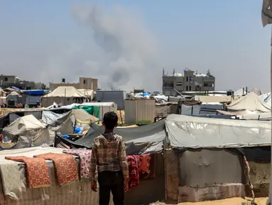 Seorang anak Palestina melihat kepulan asap mengepul dari kejauhan selama pemboman Israel di Rafah, Jalur Gaza Selatan pada 11 Juni 2025. (Foto oleh AFP)