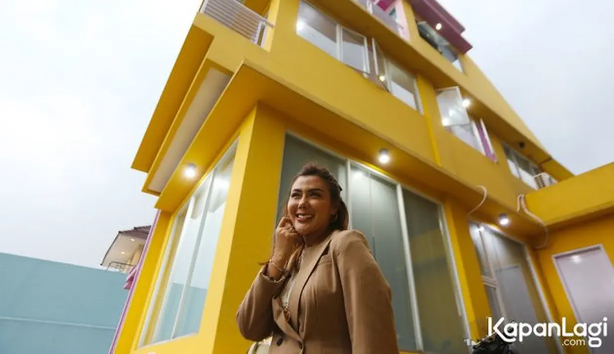 Tim Kapanlagi mendapatkan kesempatan menyambangi rumahnya. Senyum Rey Utami di depan rumahnya yang tampak megah dengan cat kuning. [Foto: KapanLagi.com®/Budy Santoso]