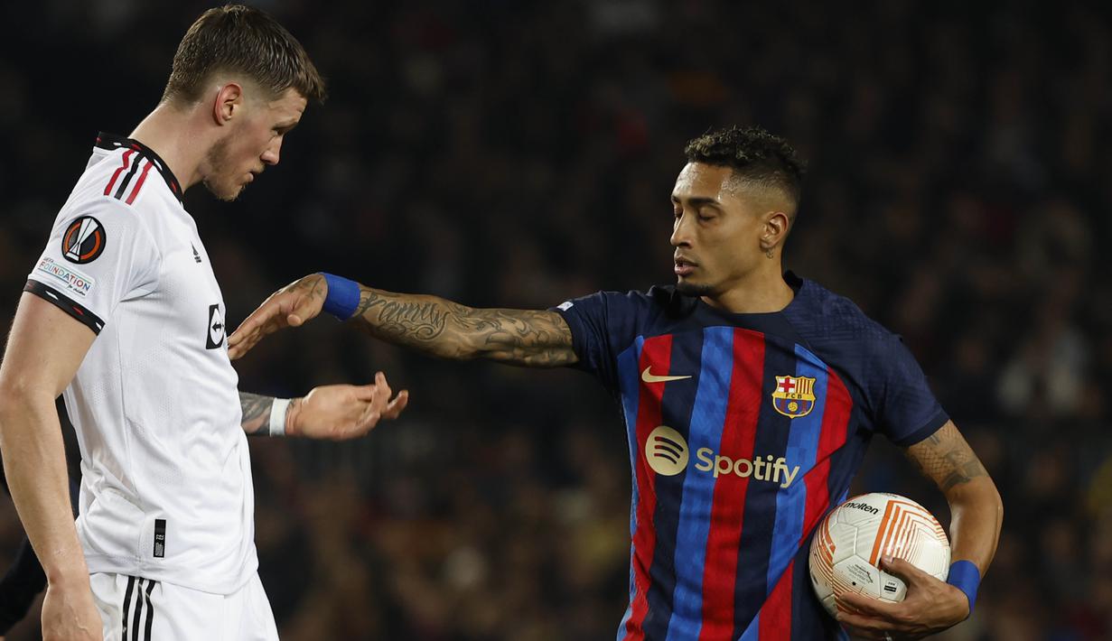 Pemain Barcelona, Raphinha bersitegang dengan pemain Manchester United, Wour Weghorst dalam pertandingan leg pertama play-off babak gugur Liga Europa 2022/2023 yang berlangsung di Camp Nou, Jumat (17/2/2023). (AP Photo/Joan Monfort)