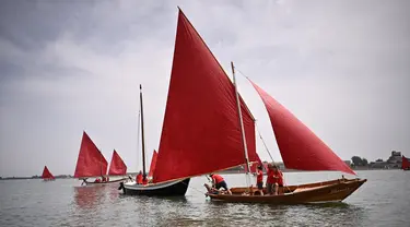 Anggota asosiasi pelayaran budaya berlayar dalam acara Regatta Merah di Venesia, Italia, Minggu (20/6/2021). Regatta Merah diselenggarakan oleh seniman AS Melissa Mc Gill. (MARCO BERTORELLO/AFP)