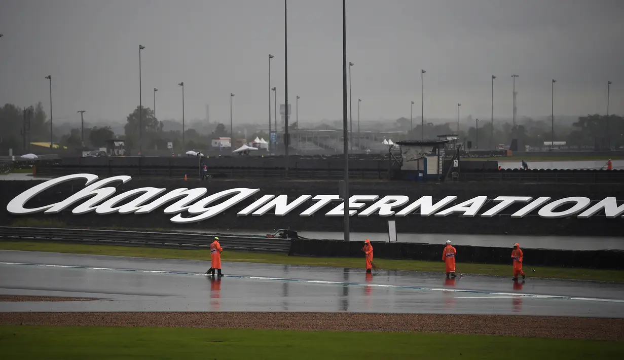 Pekerja menyapu air hujan ke luar lintasan saat sesi latihan dan kualifikasi kualifikasi MotoGP Thailand 2019 di Sirkuit Internasional Buriram, Sabtu (5/10/2019). Pekerja harus bekerja keras untuk mengeluarkan air hujan dari lintasan. (Lillian SUWANRUMPHA/AFP)