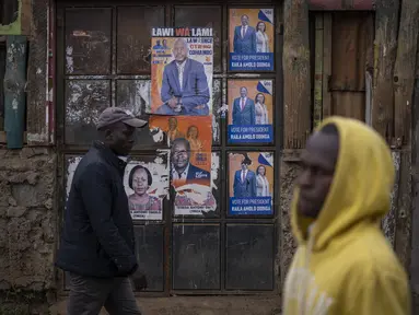 Warga berjalan melewati poster kampanye pemilihan yang menunjukkan kandidat presiden Raila Odinga dan pasangannya Martha Karua, di sebuah jalan di daerah Kibera, Nairobi, Kenya, Kamis, 11 Agustus 2022. Rakyat Kenya menunggu hasil pemilihan presiden yang berlangsung ketat namun tenang di mana jumlah pemilih lebih rendah daripada biasanya. (AP Photo/Ben Curtis)