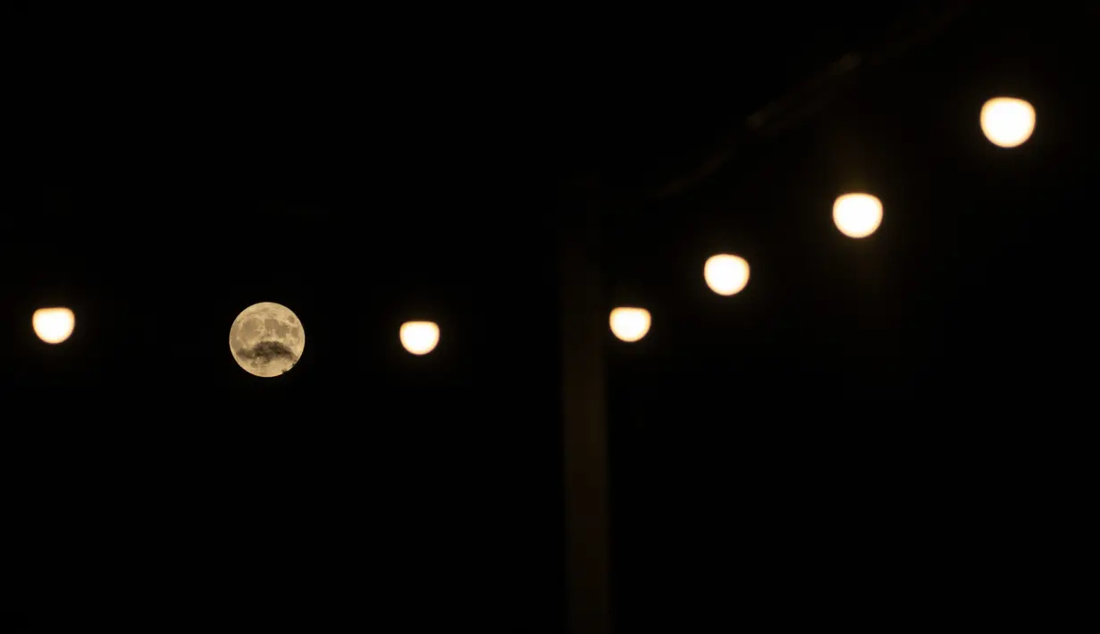 Buck Supermoon muncul di balik cahaya di dekat kota Aegio, di Peloponnese utara, Yunani, pada Rabu (13/7/2022). Bulan Purnama dikenal sebagai Buck Moon dan juga Supermoon. Fenomena tersebut hanya terjadi setiap 9 tahun sekali, dan terakhir kali muncul pada 2013 lalu. (AP Photo/Petros Giannacouris)