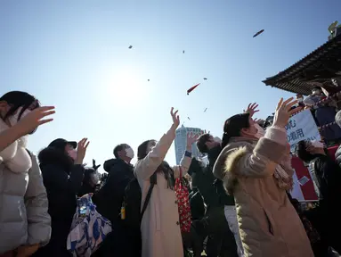 Orang-orang mencoba menangkap kacang keberuntungan yang disebarkan pada "Mame-maki," upacara pelemparan kacang di kuil Buddha Zojoji di Tokyo, 3 Februari 2022. Ritual yang diyakini membawa keberuntungan dan mengusir kejahatan dilakukan setiap tahun untuk menandai awal musim semi. (AP/Eugene Hoshiko)