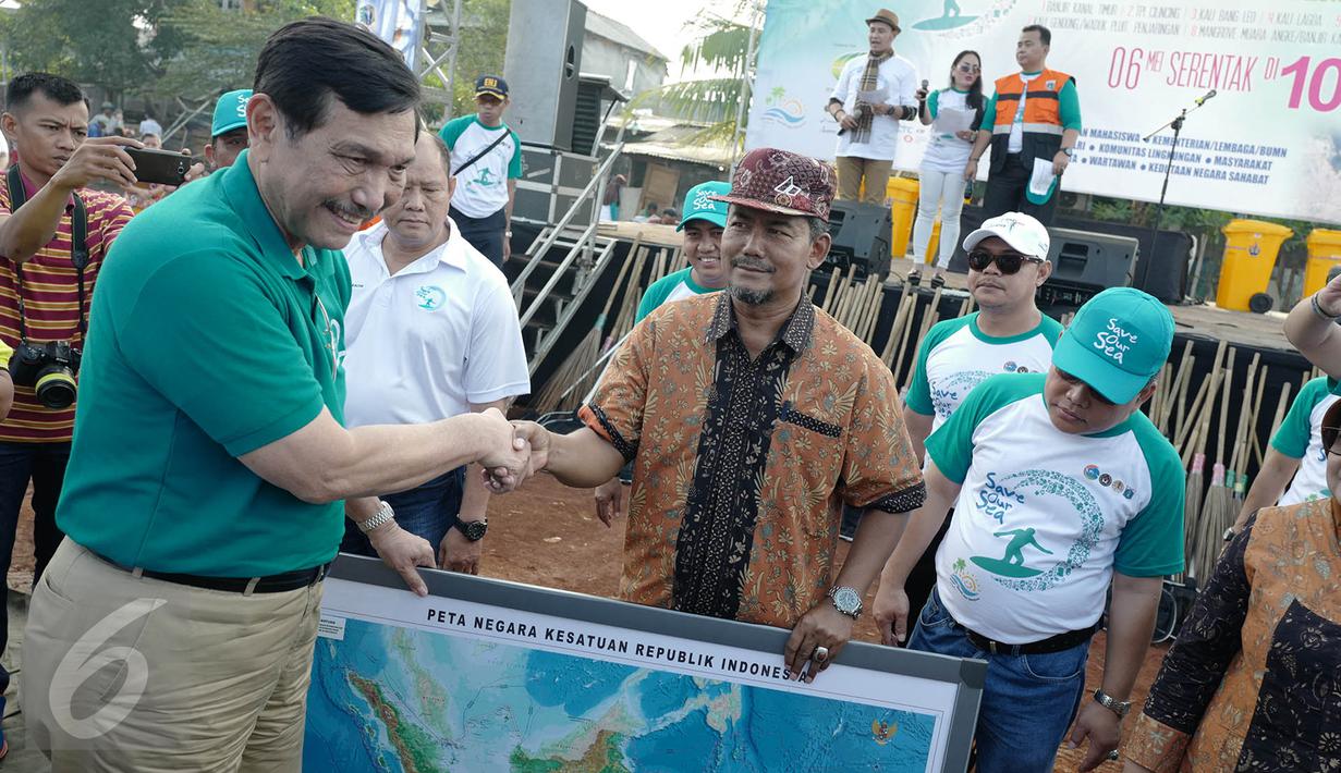 Menteri Koordinator Bidang Kemaritiman Luhut Binsar Panjaitan bersalaman dengan warga saat menggelar gerakan aksi bersih di kawasan pesisir Cilincing, Jakarta Utara, Sabtu (6/4). (Liputan6.com/Immanuel Antonius)