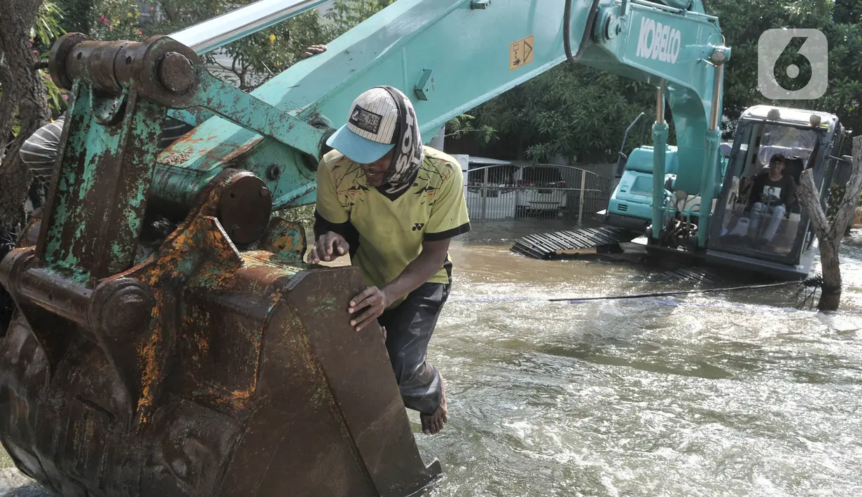 Pekerja menggunakan kendaraan alat berat saat menyelesaikan perbaikan tanggul jebol di Kompleks Perumahan Pantai Mutiara, Pluit, Jakarta, Minggu (7/6/2020). (Liputan6.com/Iqbal S. Nugroho)