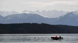 Nelayan menggunakan perahu melintas di danau Starnberger See dekat desa Starnberg, Jerman selatan, selama cuaca musim semi yang bagus dengan suhu 15 derajat pada 3 April 2018. (AFP Photo/Christof Stache)