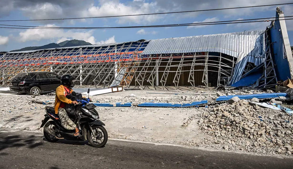 Sebuah sepeda motor melintasi di dekat bangunan yang runtuh pascagempa berkekuatan magnitudo 7,7 di Borong, Manggarai Timur, Nusa Tenggara Timur, Minggu, 16 Agustus 2026.. (AFP/ Juni Kriswanto)