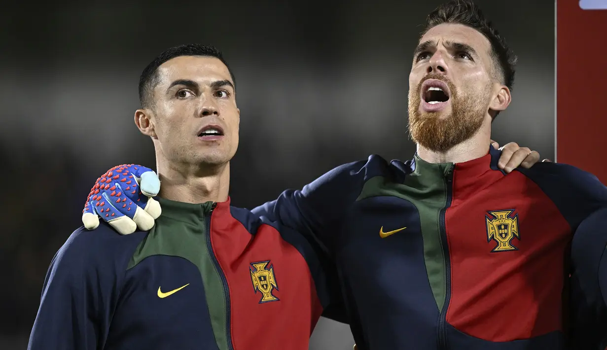 Striker Timnas Portugal, Cristiano Ronaldo (kiri) dan kiper Jose Sa berbaris menyanyikan lagu kebangsaan Portugal sebelum dimulainya laga lanjutan Grup J Kualifikasi Euro 2024 menghadapi Liechtenstein di Rheinpark Stadium, Vaduz, Jumat (17/11/2023) dini hari WIB. (Keystone via AP Photo/Gian Ehrenzeller)