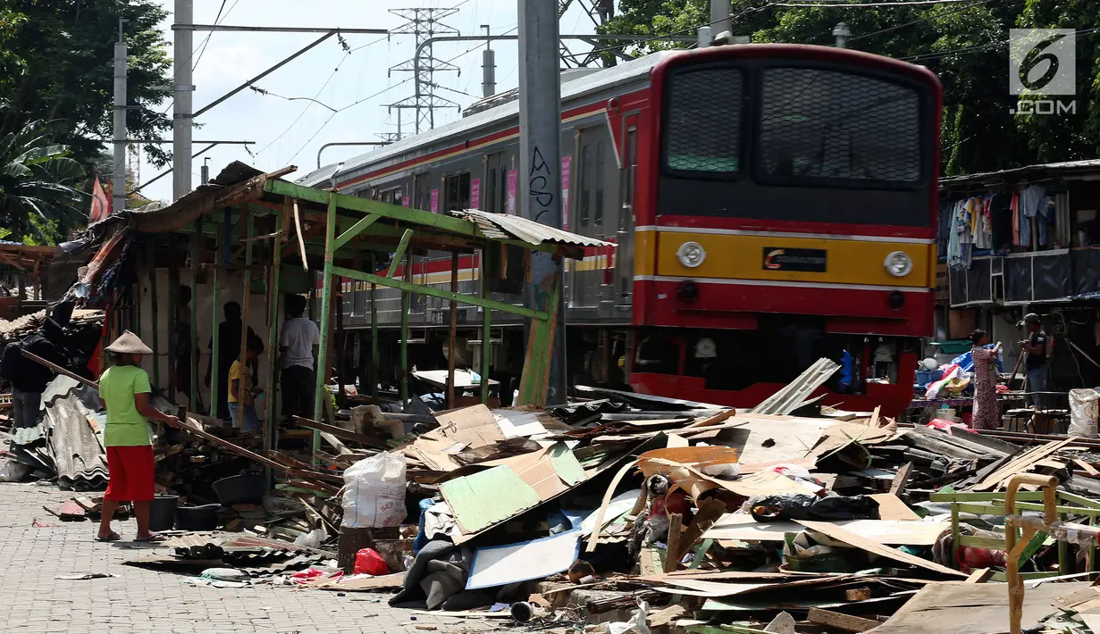 Kereta listrik melintas di sebelah bongkaran rumah di area Rusun Bendungan Hilir (Benhil) II, Jakarta, Minggu (3/12). (Liputan6.com/JohanTallo)