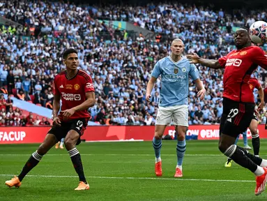 Striker Manchester City #09 Erling Haaland (tengah) melihat bek Manchester United #29 Aaron Wan-Bissaka (kanan) mengontrol bola saat ia mempertahankan gawang pada  final FA Cup 2023/2024 di Wembley Stadium, Sabtu (25/5/2024) malam WIB. (Ben Stansall / AFP)