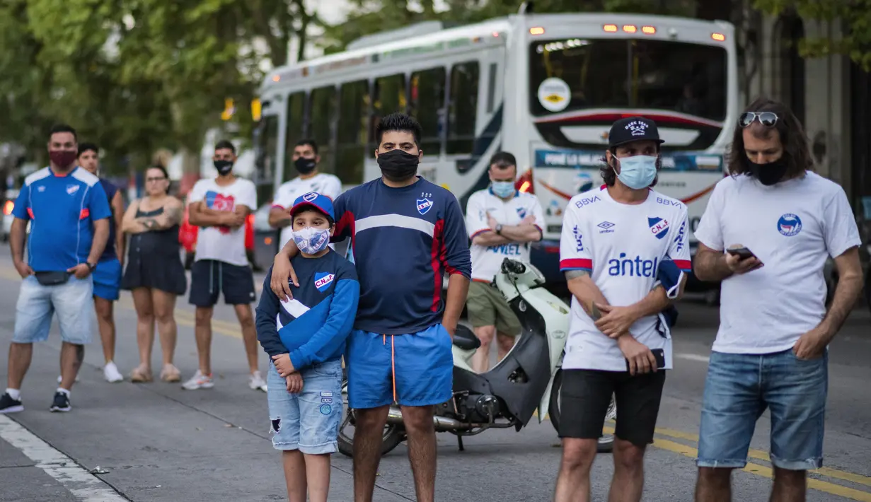 Penggemar yang berduka berkumpul di luar markas klub sepak bola Nacional untuk memberi penghormatan kepada Santiago ‘Morro’ Garcia, di Montevideo, Uruguay, Sabtu (6/2/2021). Penyerang klub Argentina Godoy Cruz tersebut ditemukan tewas diduga bunuh diri di apartemennya. (AP Photo/Matilde Campodonico)