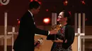 Guru sekolah Inggris, Andria Zafirakou menerima trofi Global Teacher Prize dari komedian Trevor Noah pada acara penganugerahan di Dubai, Minggu (18/3). Untuk itu Andria Zafirakou mendapatkan uang US $ 1 juta atau hampir Rp 14 miliar. (AP/Jon Gambrell)