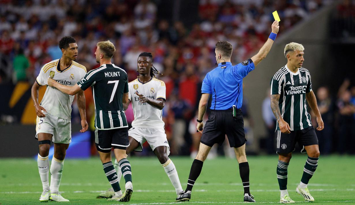 Pemain MU, Lisandro Martinez (kanan), mendapatkan hukuman kartu kuning dari wasit setelah melakukan pelanggaran keras terhadap pemain Real Madrid, Jude Bellingham (kiri), ketika kedua tim bertemu dalam pertandingan pramusim Soccer Champions Tour 2023 yang berlangsung di NRG Stadium, Houston, Kamis (27/7/23). (AFP/Getty Images/Tim Warner)