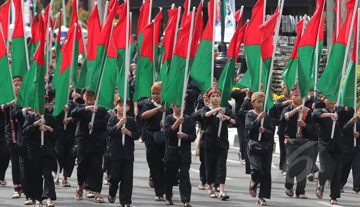 Pasukan anak-anak SD membawa bendera hijau merah berjalan bersama saat melakukan "Historical Walk" dalam peringatan ke-60 tahun Konferensi Asia Afrika di jalan Asia Afrika, Bandung, Jumat, (24/4/2015). . (Liputan6.com/Herman Zakharia)