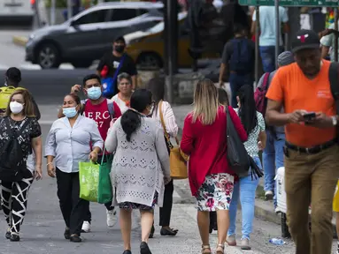 Orang-orang melintas di jalan pada hari pertama masker tidak lagi wajib di Panama City, Panama, Senin (11/7/2022). Masker tidak lagi diperlukan kecuali di rumah sakit dan transportasi umum. (AP Photo/Arnulfo Franco)