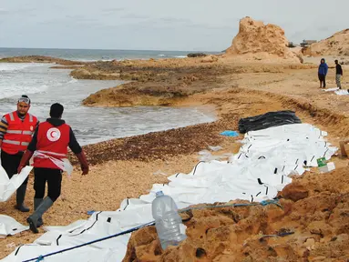 Petugas Bulan Sabit Merah Libya mengevakuasi jenazah para migran yang ditemukan terdampar di pantai utara Libya, Selasa (21/2). Sedikitnya 74 jenazah imigran tenggelam saat melintasi perairan Mediterania dalam upaya mencapai Eropa. (MOHANED KREMA/AFP)