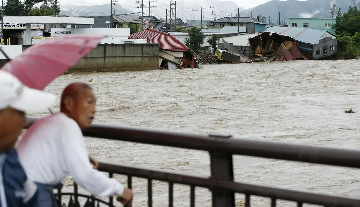 Warga menyaksikan banjir dari Sungai Kinugawa yang menerjang rumah-rumah di Joso, prefektur Ibaraki, Jepang, Kamis (10/9). Satu orang hilang dan lebih dari 90 ribu warga diperintahkan untuk mengungsi. (REUTERS/Kyodo)