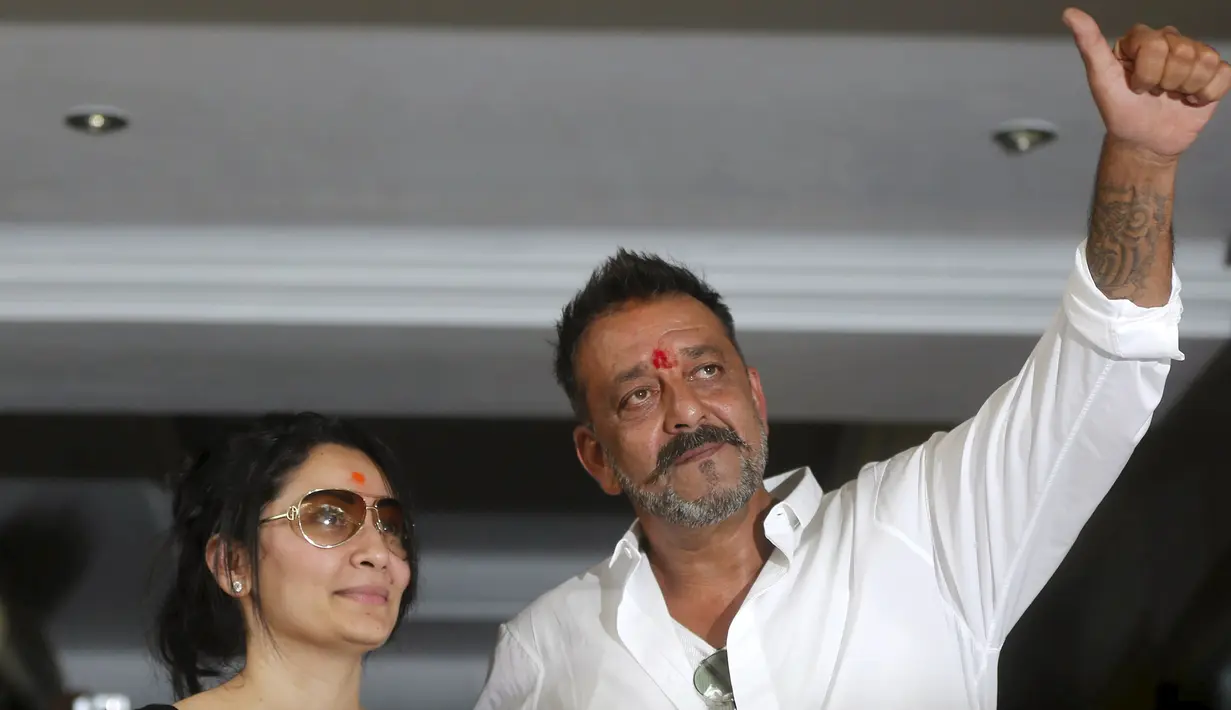 Aktor Bollywood Sanjay Dutt (kanan) mengacungkan jempol untuk para penggemarnya di kediamannya di Mumbai, India, Kamis (25/2). Sanjay telah selesai menjalani hukuman terkait keterlibatannya dalam kasus bom Mumbai pada tahun 1993 (REUTERS/Shailesh Andrade)