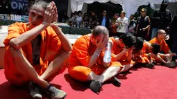 Petugas menunjukkan tersangka warga negara asing saat rilis kasus penyelundupan narkoba di Kantor Bea Cukai Ngurah Rai, Rabu (18/12/2019). Bea Cukai Ngurah Rai berhasil menangkap enam orang WNA yang berusaha menyelundupkan narkotika ke Bali selama November - Desember 2019. (AP/Firdia Lisnawati)