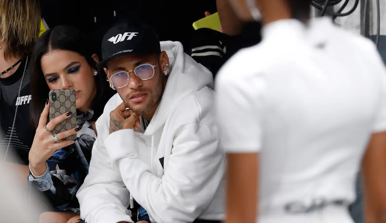 Pemain PSG, Neymar didampingi pacarnya Bruna Marquezin menghadiri acara peragaan busana Off-White Spring-Summer 2019 selama Paris Fashion Week, Prancis (27/9). Neymar tampil mengenakan jaket putih dan kaca mata emas. (AFP Photo/Francois Guillot)